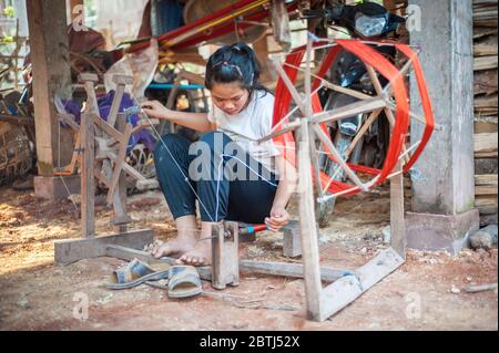 Eine laotische Frau dreht den Faden auf einem einfachen hölzernen Spinnrad, Nord-Laos, Südostasien Stockfoto