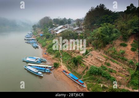 Langsame Holzboote auf dem Mekong-Fluss während eines nebligen Morgens, Nord-Laos, Südostasien Stockfoto