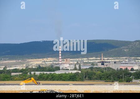 Der Kamin des Heizraums ist rauchend. Heizraum entfernt im Feld. Stockfoto