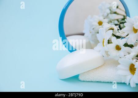 Artikel für die tägliche Pflege: Weißes Frottee-Handtuch, blauer Spiegel und weiße Seife. Stockfoto