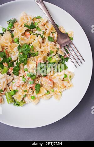 Farfalle Pasta mit Lachs und Erbsen auf einem Teller Stockfoto