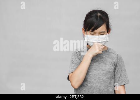 Asiatisches kleines Mädchen trägt hygienische Maske, um das Virus, PM2.5, Coronavirus, (2019-nCoV) zu verhindern. Asiatisch kleines Mädchen Gefühl unwohl und husten isoliert Stockfoto