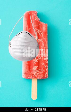 Erdbeerpopsicles mit schützender Gesichtsmaske auf blauem Hintergrund Stockfoto