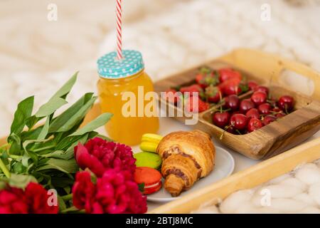 Frühstück im Bett mit Kaffee, Croissants, Erdbeeren und Saft Stockfoto