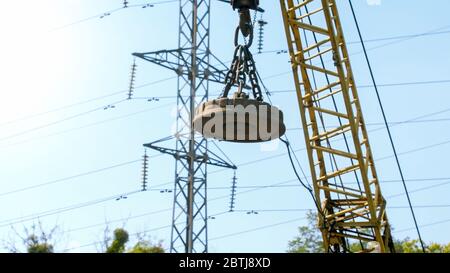 Bild eines großen elektrischen Magneten, der auf dem Kran auf dem Dump hängt Stockfoto