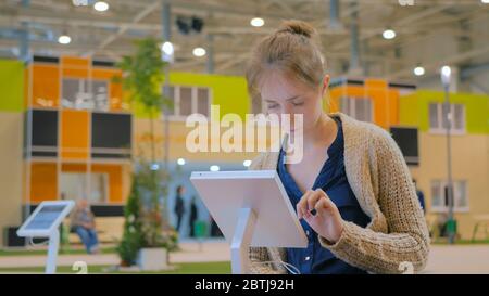 Frau mit interaktiven Touchscreen Display an den städtischen Ausstellung - Scrollen und berührend. Entertainment und Technologie Konzept Stockfoto