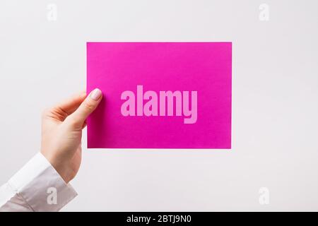 Die Hand der Frau hält leeres Papier von brigth rosa Farbe Stockfoto