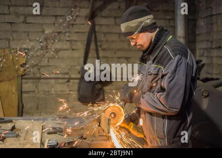 Professionelle schmied Sägen von Metall mit der Kreissäge in der Schmiede, Werkstatt. Handarbeit, Handwerk und Schmiedekunst Konzept Stockfoto