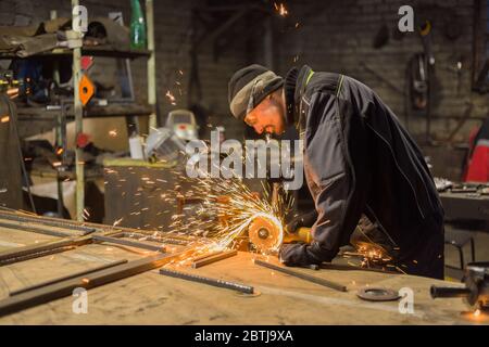 Professionelle schmied Sägen von Metall mit der Kreissäge in der Schmiede, Werkstatt. Handarbeit, Handwerk und Schmiedekunst Konzept Stockfoto