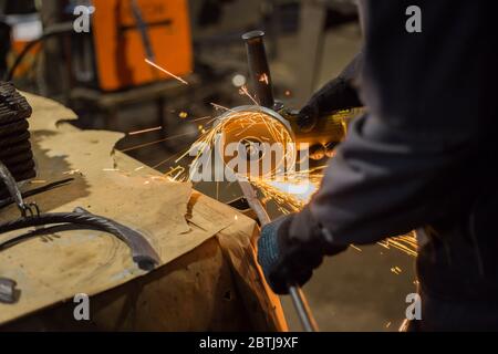 Professionelle schmied Sägen von Metall mit der Kreissäge in der Schmiede, Werkstatt. Handarbeit, Handwerk und Schmiedekunst Konzept Stockfoto