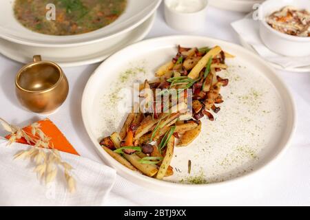 Bratkartoffeln mit Pilzen auf weißem Teller Stockfoto