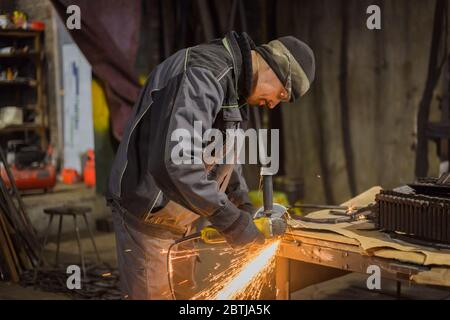 Professionelle schmied Sägen von Metall mit der Kreissäge in der Schmiede, Werkstatt. Handarbeit, Handwerk und Schmiedekunst Konzept Stockfoto