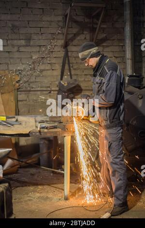 Professionelle schmied Sägen von Metall mit der Kreissäge in der Schmiede, Werkstatt. Handarbeit, Handwerk und Schmiedekunst Konzept Stockfoto