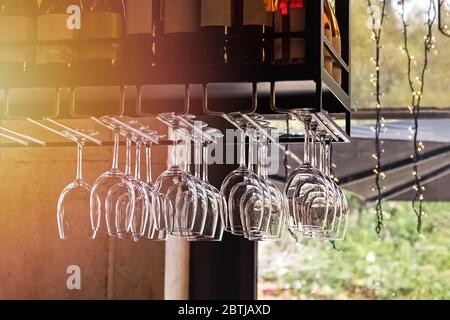 Die sauberen Gläser für den Wein hängen in den Befestigungen in den geraden Reihen in der Bar Stockfoto