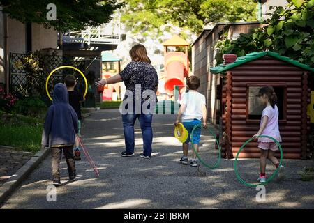 Ivrea, Italien - 26. Mai 2020: Ein Lehrer spielt mit Kindergartenkindern in einem Schulgarten. Die Gemeinde Ivrea eröffnet die Gärten zweier Kindergartenschulen im Rahmen eines Pilottests, um zu sehen, wie die Schulen nach der Sperrung des Coronavirus COVID-19 wieder eröffnet werden können. Quelle: Nicolò Campo/Alamy Live News Stockfoto