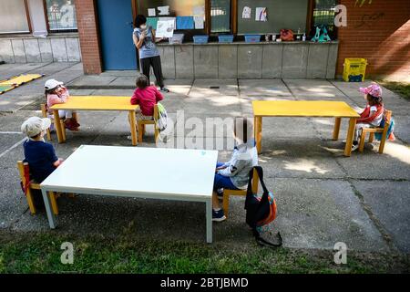 Ivrea, Italien - 26. Mai 2020: Ein Lehrer liest ein Buch zu den Kindergartenkindern in einem Schulgarten. Die Gemeinde Ivrea eröffnet die Gärten zweier Kindergartenschulen im Rahmen eines Pilottests, um zu sehen, wie die Schulen nach der Sperrung des Coronavirus COVID-19 wieder eröffnet werden können. Quelle: Nicolò Campo/Alamy Live News Stockfoto
