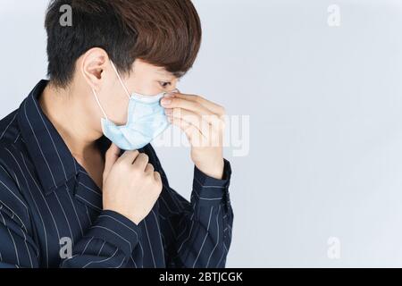 Asian gut aussehend glücklich Hipster Mann trägt eine medizinische Schutz Gesichtsmaske zum Schutz der Coronavirus, Filterstaub PM 2.5 und Kälte auf weißem Hintergrund Stockfoto