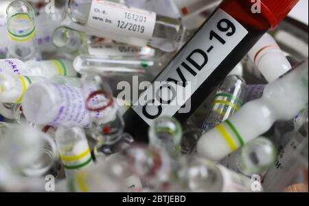Viersen, Deutschland - Mai 26. 2020: Nahaufnahme der Blutprobenflasche mit Text covid-19 auf einem Haufen von Drogenampullen (Fokus auf Blutgefäß) Stockfoto