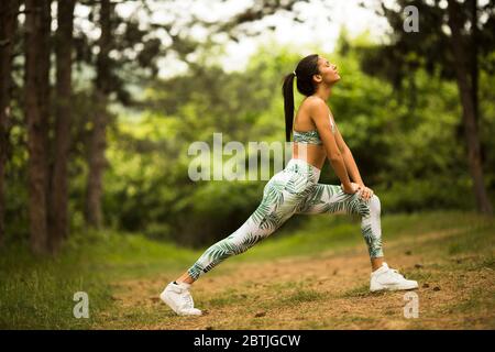 Hübsche junge Frau Stretching und atmen frische Luft in der Mitte des Waldes beim Training Stockfoto