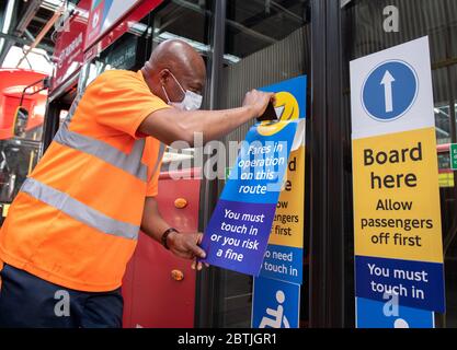 Mitarbeiter der Arriva-Busgarage, die Aufkleber an Londoner Bussen anbringen, erinnern die Passagiere daran, für ihre Reise zu bezahlen, indem sie während der COVID an Bord gehen Stockfoto