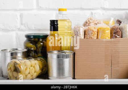 Set von ungekochten Lebensmitteln auf Speisekammer Regal für Katastrophen Notsituationen auf Backstein Wand Hintergrund Nahaufnahme vorbereitet Stockfoto