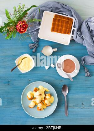 Hefegebäck mit Zabaglione oder Vanillecreme, süßem Dessert oder Hauptgericht. Draufsicht. Blauer Holzhintergrund. Stockfoto