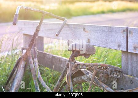 Ein altes verlassene rostige Fahrrad parkte gegen Holzzaun. Altmodische klassische Fahrrad steht vergessen entlang eines Radweges. Aus dem Graben gefischt Stockfoto