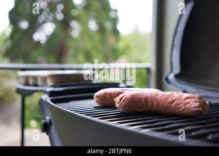 Auf pflanzlicher Basis werden neben Fleischwürsten auf dem Grill Würstchen serviert. Selektiver Fokus auf einen der veganen Wurstenden. Stockfoto