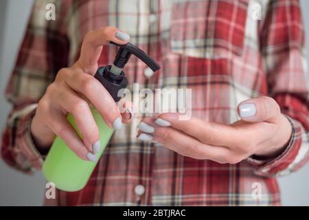 Frau drückt Spender, drückt antiseptisches Gel auf die Handfläche, reinigt die Hände - Nahaufnahme von vorne. Desinfektion, Schutz, Prävention, COVID-19 Stockfoto