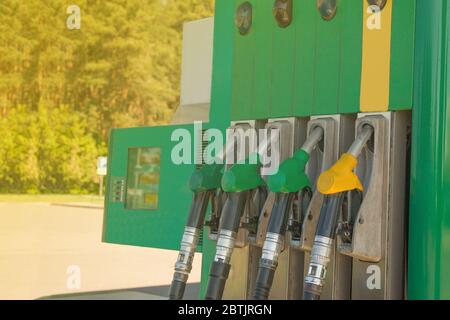 Tankstelle mit den Strahlen der Sonne. Bunte Zapfventile für die Benzinpumpe. Kraftstofföl-Benzinspender an der Tankstelle Stockfoto