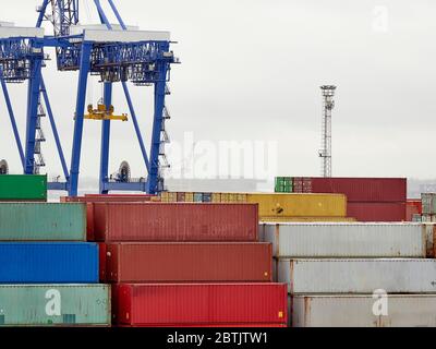Container im Hafen von Felixstowe stapelten sich vor Kränen und einem weiteren Hafen in der Ferne. Stockfoto