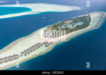 Luftaufnahme einer tropischen Insel im türkisfarbenen Wasser. Luxuriöse Überwasser-Villen auf tropischen Inselresort Malediven für Urlaub Hintergrund Stockfoto