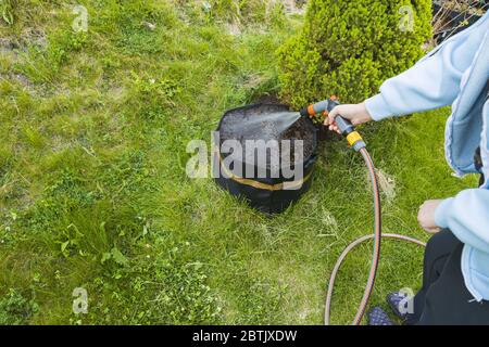 Ansicht der weiblichen Bewässerungspflanzen in Lufttöpfen. Gartenbau Konzept schöne Hintergründe. Stockfoto