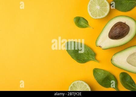 Oben über der Ansicht von oben beschnittenes Foto von geschnittenen Avocado, Zitronenscheiben und Babyspinat Blätter Plätze auf der rechten Seite isoliert auf gelbem Hintergrund Stockfoto