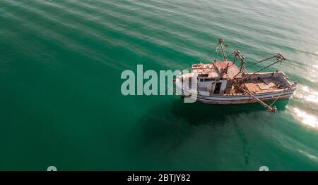 Luftaufnahme eines Fischerbootes, das allein auf der kolumbianischen Karibik schwimmt und smaragdgrünes und blaues Wasser und pazifische Wellen zeigt Stockfoto