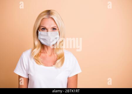 Nahaufnahme Foto von mittleren Alters Dame haben Breating Maske gut aussehende Aufenthalt zu Hause Konzept tragen weißen lässig T-Shirt isoliert pastellbeige Hintergrund Stockfoto
