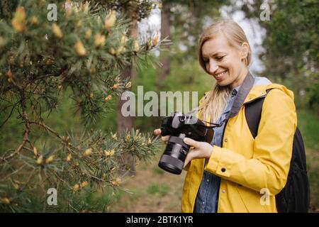 Glückliche Frau Überprüfung der aufgenommenen Fotos vor der Kamera im Wald Stockfoto