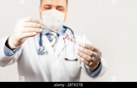 Test auf Coronavirus Covid-19. Männlicher Arzt oder Krankenschwester, der Nasenabstrich im Labor eines Krankenhauses analysiert. Ein Medizintechniker hält ein COVID-19-Schmierset mit Schutzhandschuhen in der Hand. Stockfoto