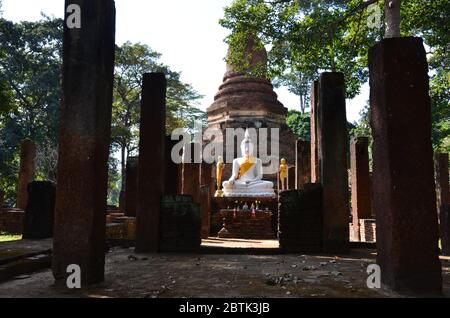 Weißer Buddha sitzt vor einem schönen Chedi im Wat Chang in Kamphaeng Phet Stockfoto