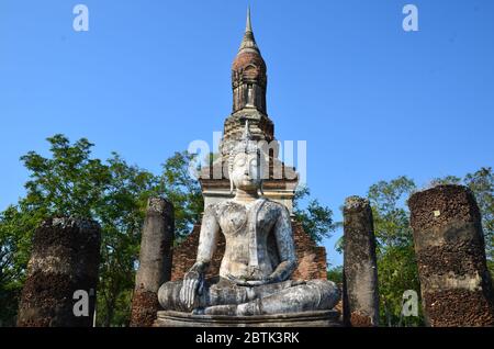 Wunderbarer weißer Buddha, der vor dem Chedi des Wat Traphang Ngoen, Sukhothai Historical Park, sitzt Stockfoto