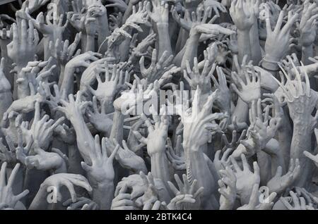 Hände verlorener Menschen reichen aus der Hölle den Wat Rong Khon, den schönen weißen Tempel in Chiang Rai Stockfoto