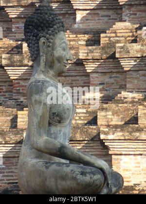 Wunderschöne sitzende Buddha-Statue vor einem Chedi im Wat Mahathat, Sukhothai Stockfoto