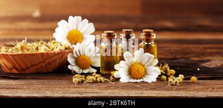 Kamille Komposition mit ätherischem Öl und Kamillenblüten auf rustikalem Holztisch Stockfoto