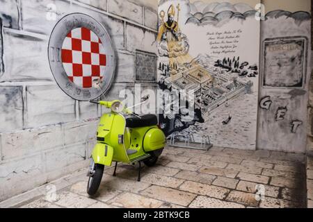 Grüne vespa neben Steinmauer, die ein gemaltes Logo des kroatischen Fußballclubs HNK Hajduk Split, in der Altstadt zeigt geparkt Stockfoto