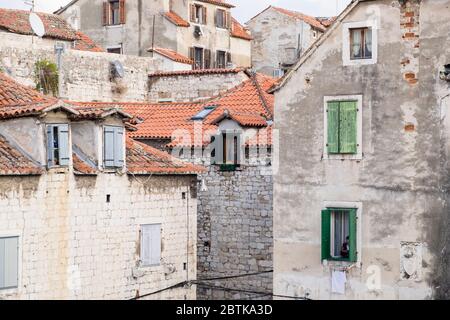 Kroatische Frau leicht versteckt im Fenster ihres Hauses, während sie auf ihr Handy, Altstadt, Split, Kroatien schaut Stockfoto