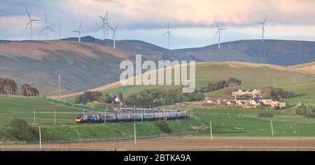 Virgin Züge Alstom Pendolino Zug auf der Westküste Hauptlinie im oberen Clyde Tal, Schottland mit einem Windpark zeigt grünen Transport Stockfoto