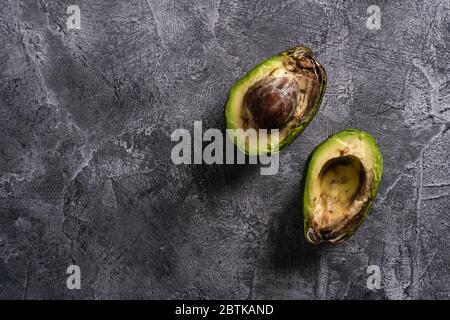 Faule Avocado, halb geschnittenes Obst, Freegan Food Konzept, grauer Hintergrund, Ansicht von oben Kopierraum Stockfoto