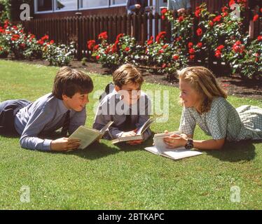 Schulkinder liegen auf dem Rasen in der Schule, Surrey, England, Großbritannien Stockfoto