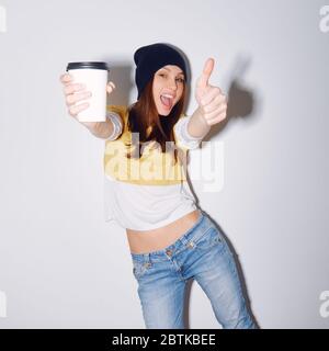 Nahaufnahme Studio Schuss von hübschen Hipster Teenager-Mädchen mit Mütze Hut halten Kopf machen lustige Gesicht. Zeigt Hand ok Stockfoto