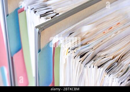 Nahaufnahme von Ordnern mit Papier und Tabs. Stapel von Geschäftsunterlagen, Rechnungen oder Dokumenten in stehenden Aktenordnern. Schuldenfreies Leben, papierloses Büro. Stockfoto